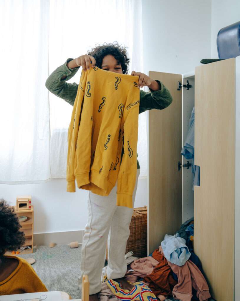 Black teenager choosing clothes in bedroom