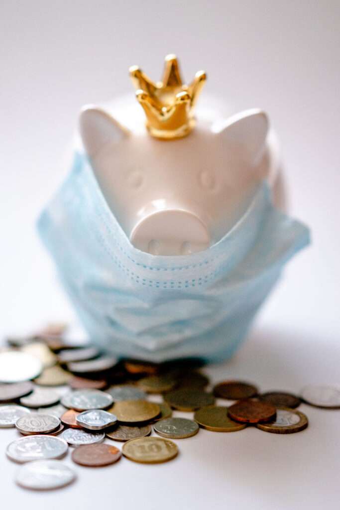Piggy bank in protective mask and crown with coins